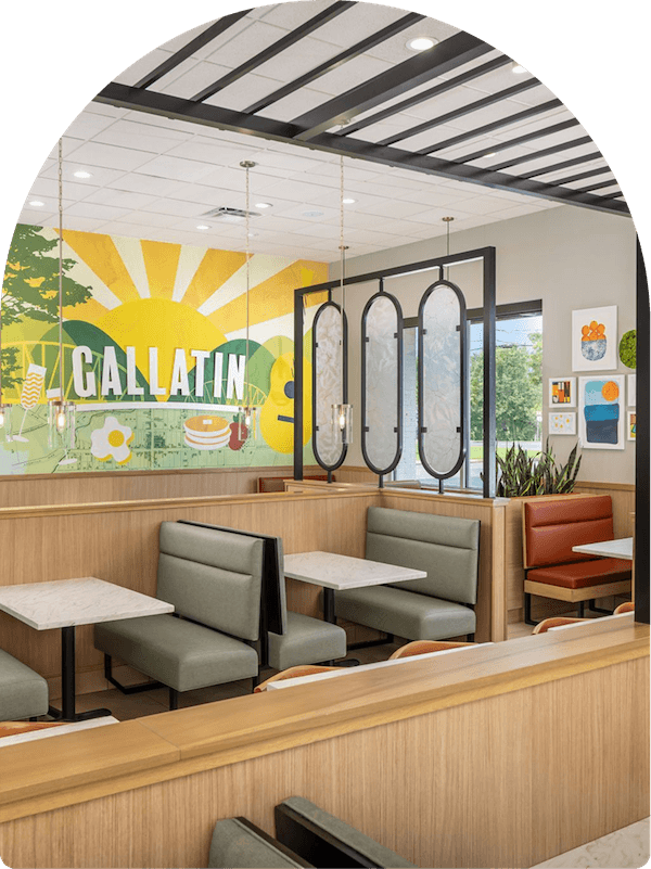 Interior of Keke's Breakfast Cafe in Gallatin featuring booth seating, marble tables, and a custom sunrise mural
