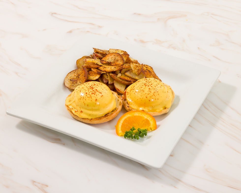 Eggs Benedict with orange slice and Home Fries on plate