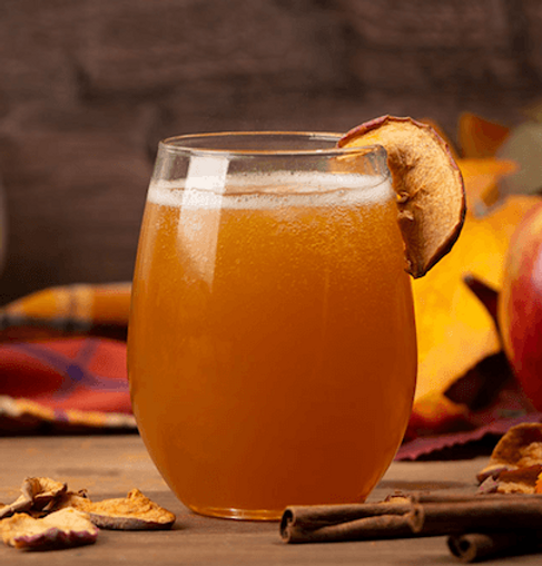 Apple cider mimosa topped with sparkling wine and crunchy apple chips in a glass mug