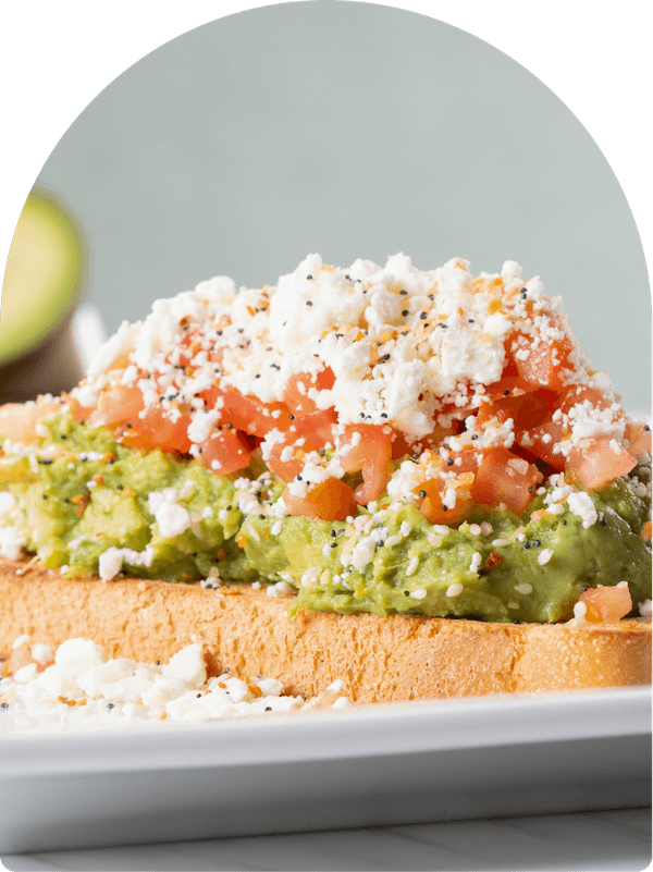 Keke's Breakfast Cafe avocado toast topped with everything seasoning, feta cheese, and diced tomatoes on thick-cut bread