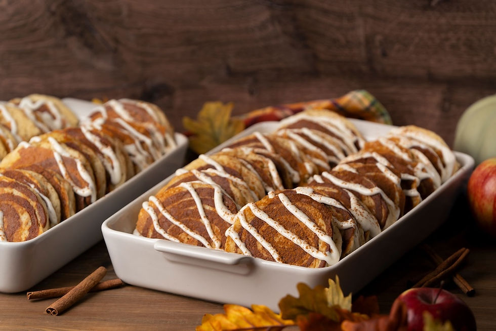 Stack of cinnamon roll pancakes topped with cream cheese icing and cinnamon, served in catering dish